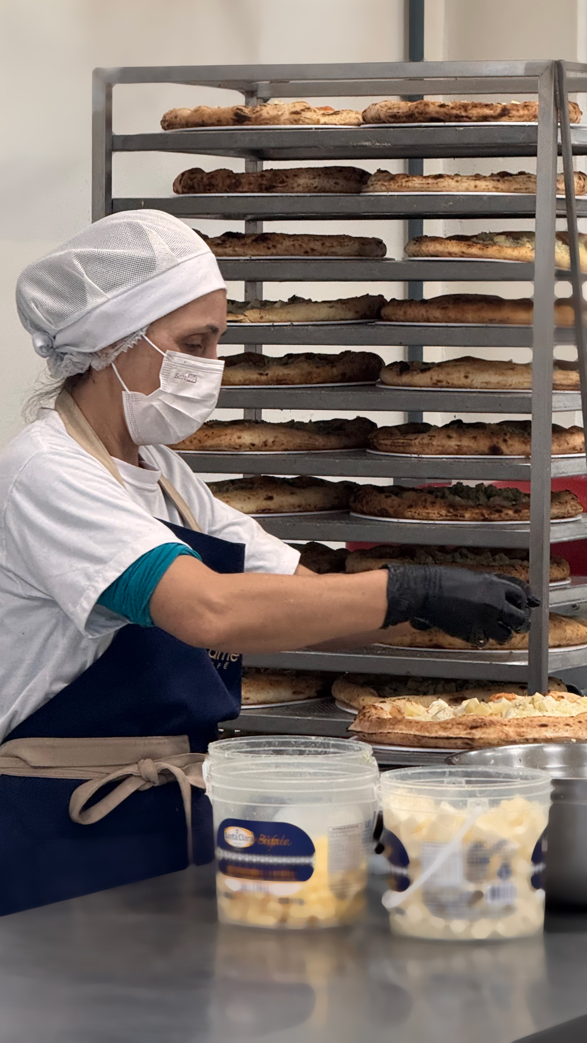 Funcionária organizando pizzas no rack de refrigeração e congelamento rápido