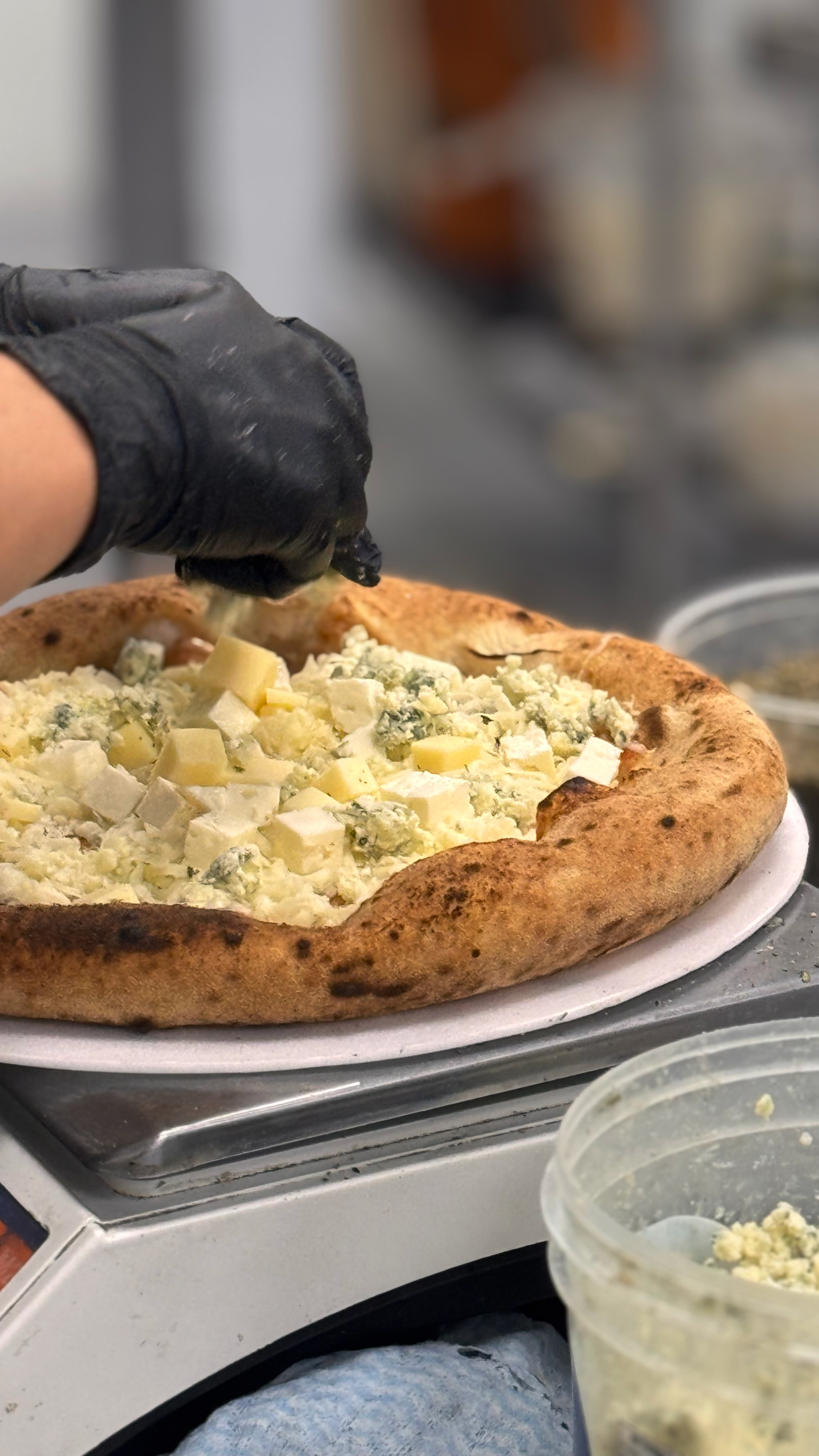 Dafra Congelados processo artesanal polvilhando queijo parmesão sobre massa de pizza